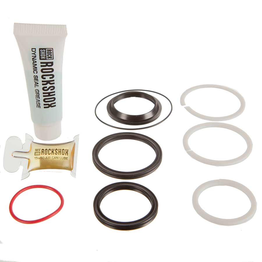 RockShox 50-hour service kit for Deluxe/Super Deluxe shocks with Dynamic Seal Grease tube, air-can lube packet, seals, and glide rings on white.