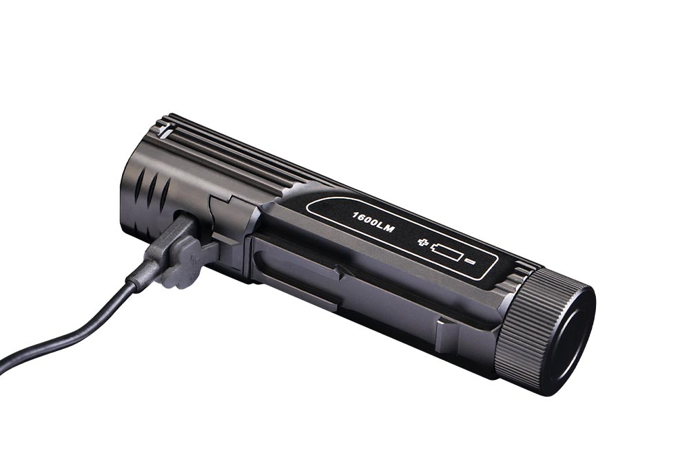 Fenix BC26R bike light with USB Type-C charging cable plugged in; 1600LM marking and battery level indicator visible on black aluminum body